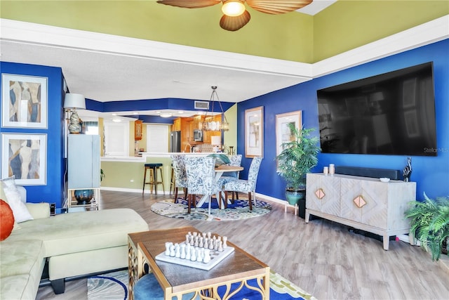 living room with a ceiling fan, baseboards, and wood finished floors