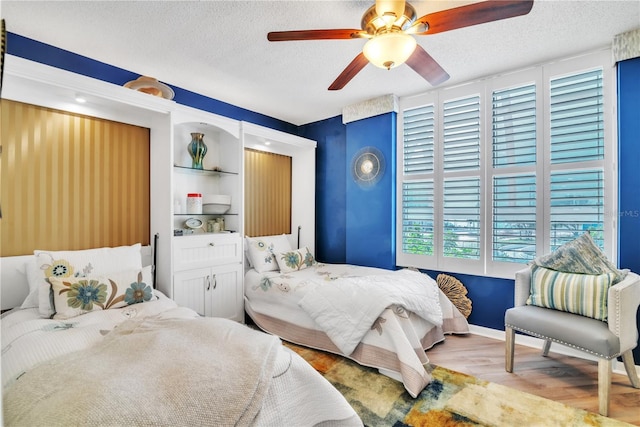 bedroom with baseboards, a textured ceiling, ceiling fan, and wood finished floors