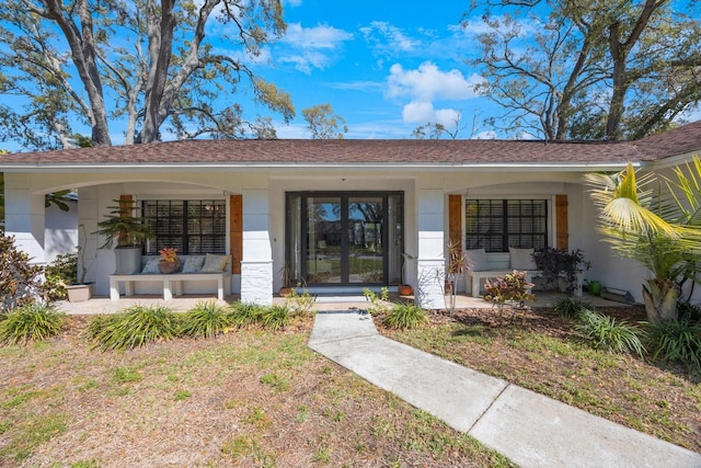 view of front of home with stucco siding, covered porch, and a shingled roof