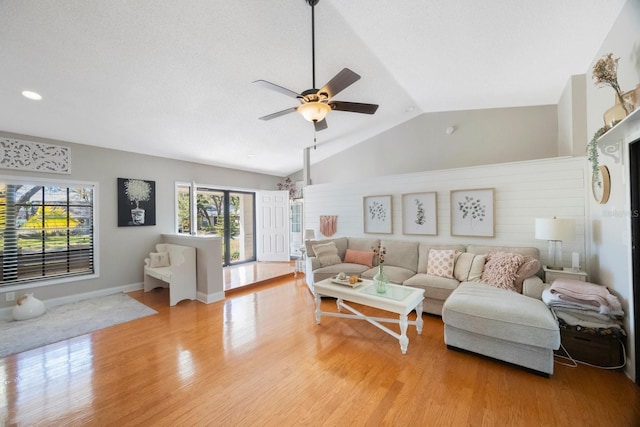 living room featuring baseboards, light wood-style floors, a ceiling fan, and vaulted ceiling