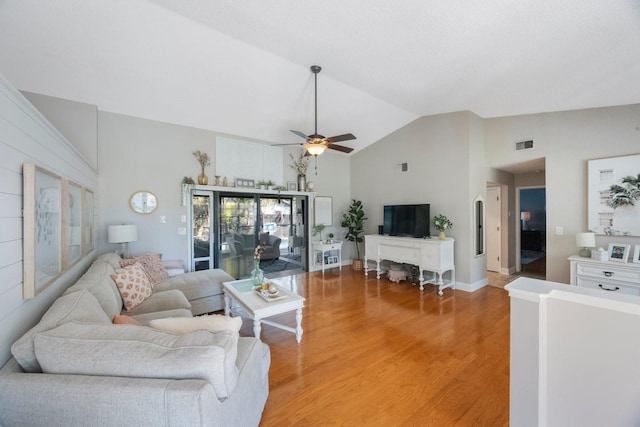 living area featuring a ceiling fan, visible vents, light wood finished floors, and high vaulted ceiling