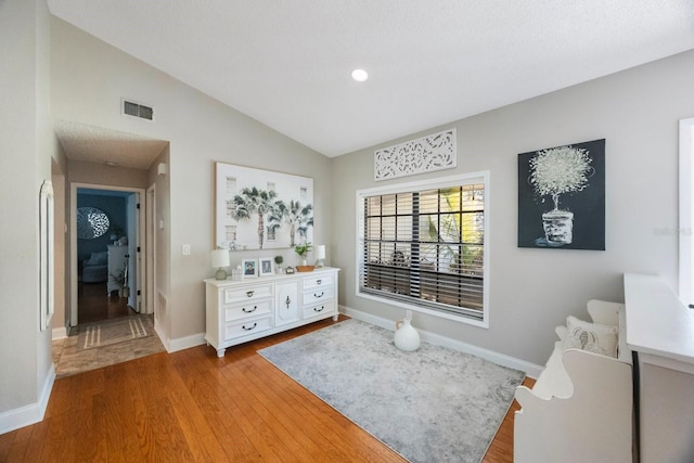 sitting room with visible vents, baseboards, wood finished floors, and vaulted ceiling