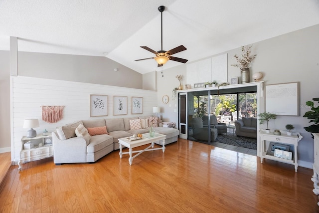 living area with high vaulted ceiling, a ceiling fan, and light wood-style floors