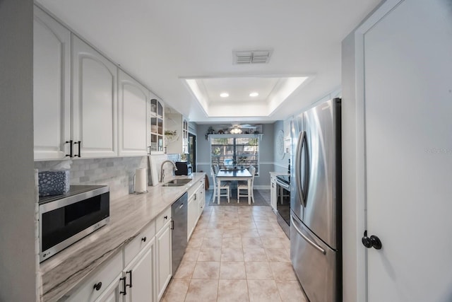 kitchen featuring visible vents, a sink, white cabinets, appliances with stainless steel finishes, and a raised ceiling