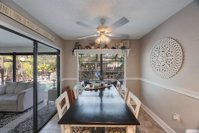 dining room with a textured ceiling, light tile patterned floors, baseboards, and ceiling fan