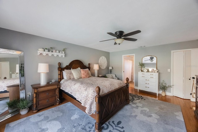 bedroom featuring baseboards, wood finished floors, visible vents, and ceiling fan