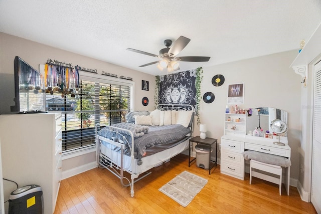 bedroom featuring ceiling fan, light wood-style flooring, baseboards, and a textured ceiling