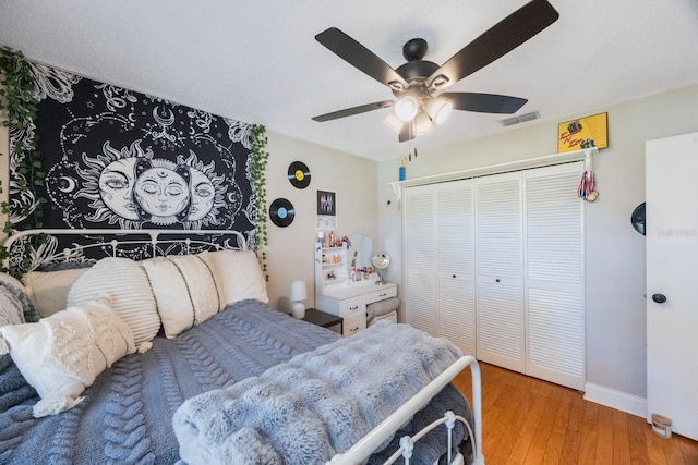 bedroom featuring visible vents, baseboards, ceiling fan, wood finished floors, and a closet