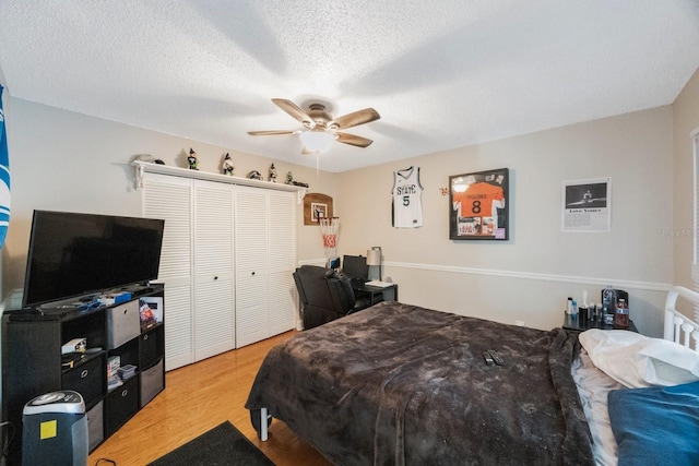 bedroom featuring a closet, a textured ceiling, a ceiling fan, and wood finished floors