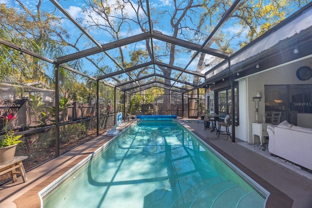 view of pool with glass enclosure, a patio area, a fenced backyard, and a fenced in pool