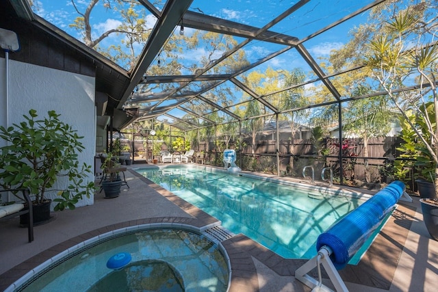 view of swimming pool featuring a lanai, a pool with connected hot tub, a patio, and fence