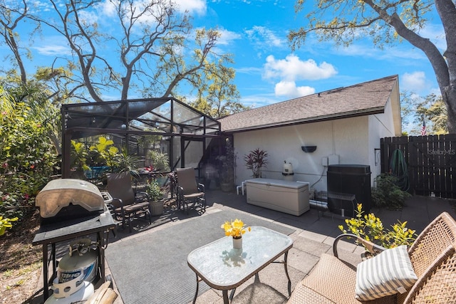 view of patio with area for grilling, a lanai, and fence