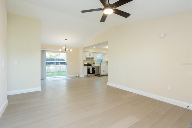 interior space featuring light wood finished floors, baseboards, lofted ceiling, ceiling fan with notable chandelier, and a sink