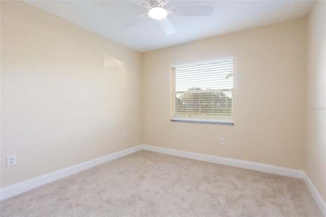 spare room featuring baseboards, light colored carpet, and a ceiling fan