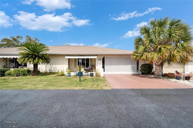 view of front facade with concrete driveway, a garage, a front yard, and stucco siding