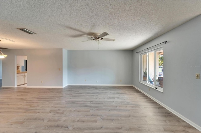 empty room with baseboards, wood finished floors, visible vents, and ceiling fan