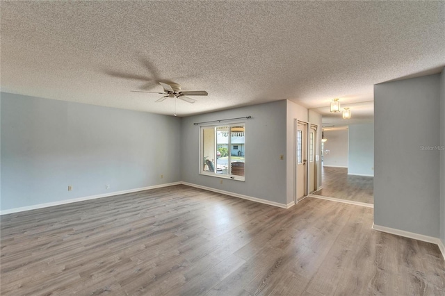 spare room featuring a textured ceiling, wood finished floors, baseboards, and ceiling fan