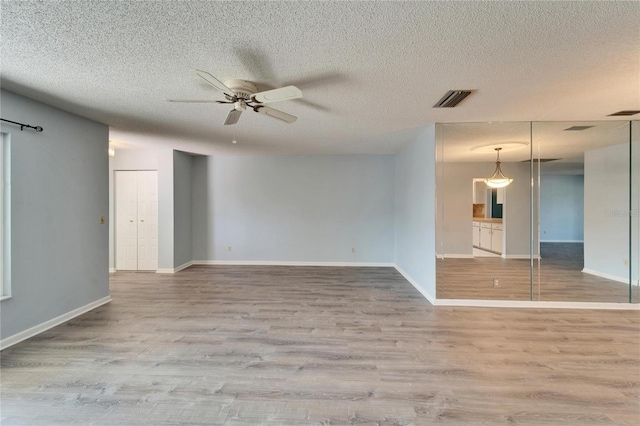 unfurnished room with visible vents, baseboards, ceiling fan, and wood finished floors