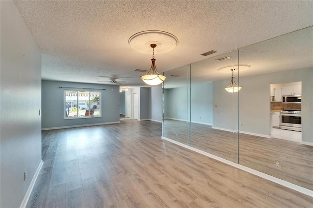 unfurnished living room featuring baseboards, visible vents, light wood finished floors, and ceiling fan