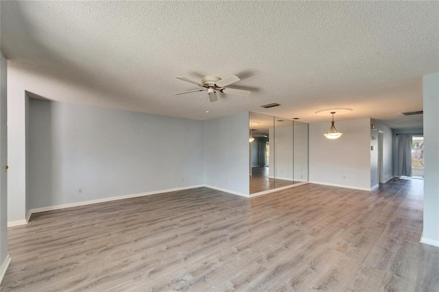 unfurnished living room with visible vents, ceiling fan, baseboards, and wood finished floors