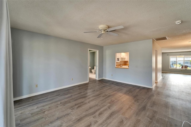 spare room featuring visible vents, baseboards, ceiling fan, and dark wood-style flooring