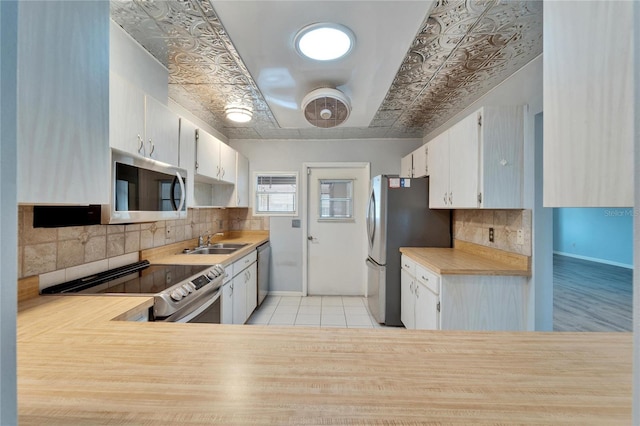 kitchen featuring a sink, stainless steel appliances, backsplash, and light countertops