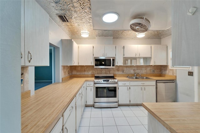 kitchen with an ornate ceiling, a sink, light countertops, appliances with stainless steel finishes, and tasteful backsplash