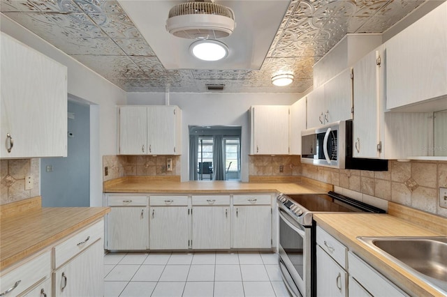 kitchen with light countertops, an ornate ceiling, light tile patterned flooring, and appliances with stainless steel finishes