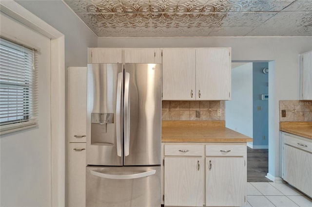 kitchen featuring backsplash, stainless steel fridge, an ornate ceiling, and light countertops