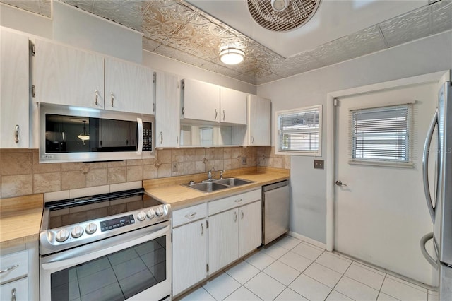 kitchen with an ornate ceiling, a sink, light countertops, appliances with stainless steel finishes, and backsplash