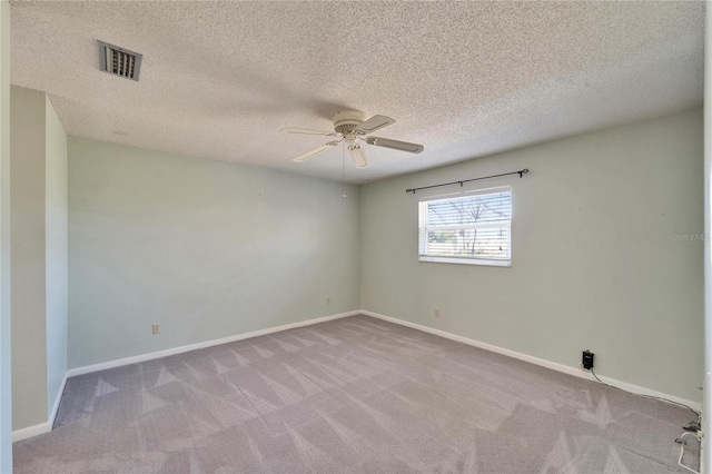 carpeted spare room featuring visible vents, a textured ceiling, baseboards, and ceiling fan