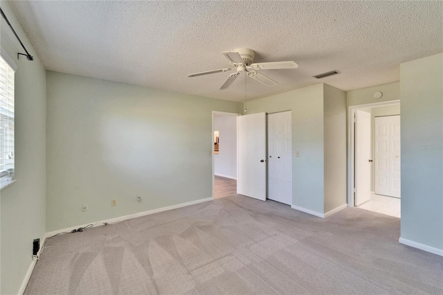 unfurnished bedroom with visible vents, carpet floors, a textured ceiling, and baseboards