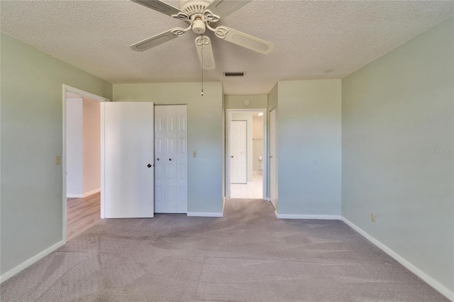 unfurnished bedroom featuring visible vents, a textured ceiling, carpet, and baseboards