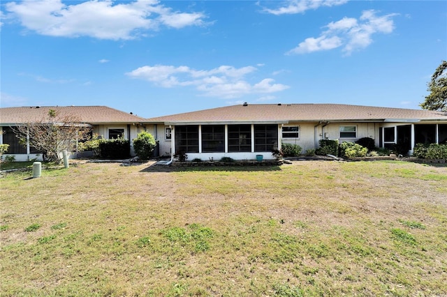 rear view of house featuring a lawn and a sunroom