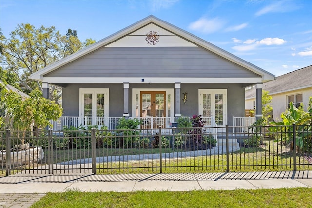 view of front facade with a porch, french doors, a fenced front yard, and stucco siding