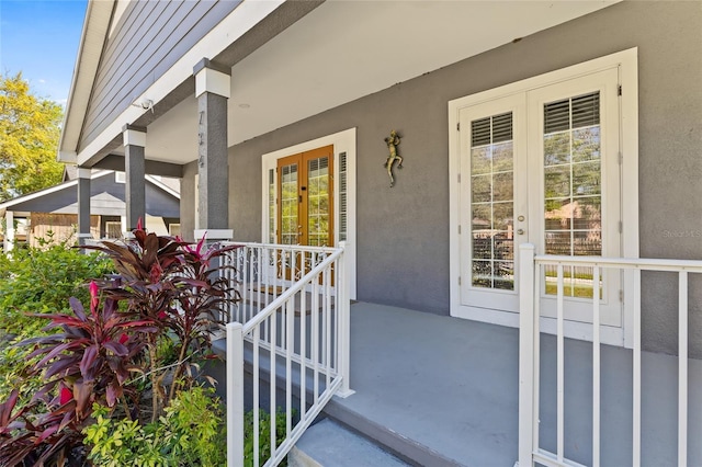 entrance to property with a porch, french doors, and stucco siding