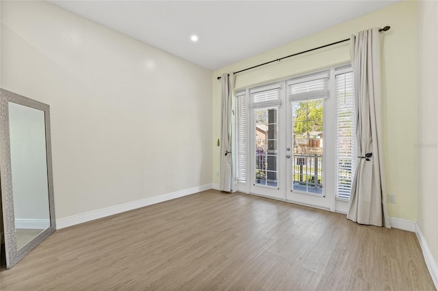 spare room featuring french doors, baseboards, and wood finished floors