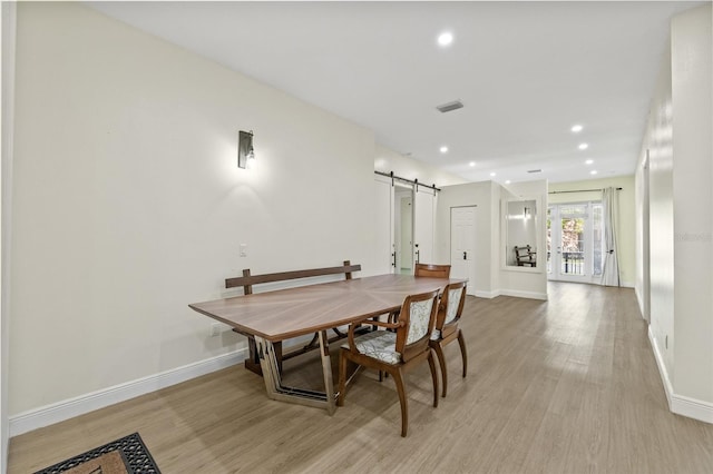 dining room with baseboards, light wood-style floors, and a barn door