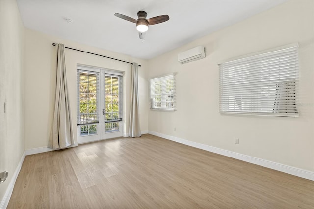 spare room featuring baseboards, ceiling fan, a wall mounted air conditioner, french doors, and wood finished floors