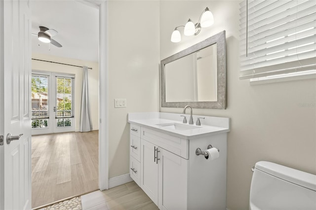 bathroom with baseboards, toilet, wood finished floors, and vanity