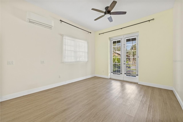 unfurnished room with an AC wall unit, a ceiling fan, wood finished floors, french doors, and baseboards