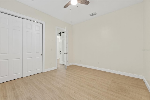 unfurnished bedroom with a closet, baseboards, visible vents, and light wood finished floors