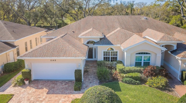 view of front of home with stucco siding, decorative driveway, and a garage