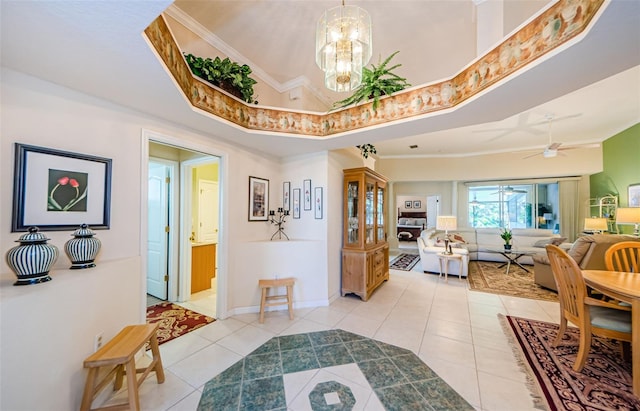 foyer with light tile patterned floors, a tray ceiling, baseboards, and ornamental molding