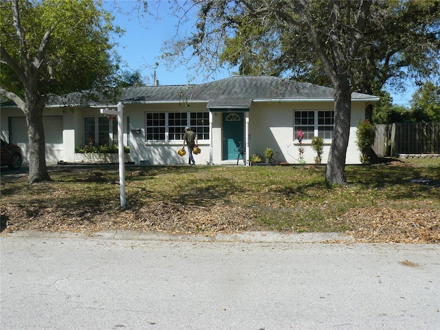 ranch-style house featuring stucco siding and fence