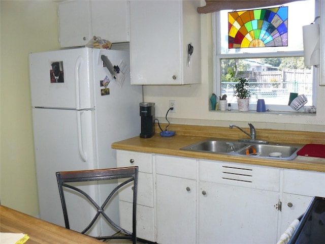 kitchen with a sink, white cabinetry, light countertops, and freestanding refrigerator