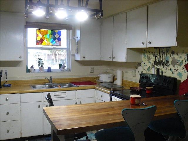 kitchen featuring white cabinets, black electric range oven, and a sink