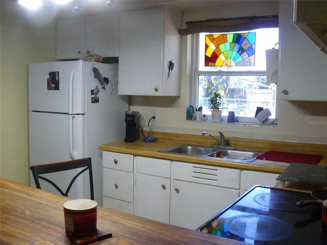 kitchen featuring a sink, white cabinetry, light countertops, and freestanding refrigerator