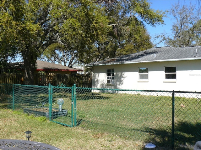 exterior space with stucco siding, a lawn, a shingled roof, and fence