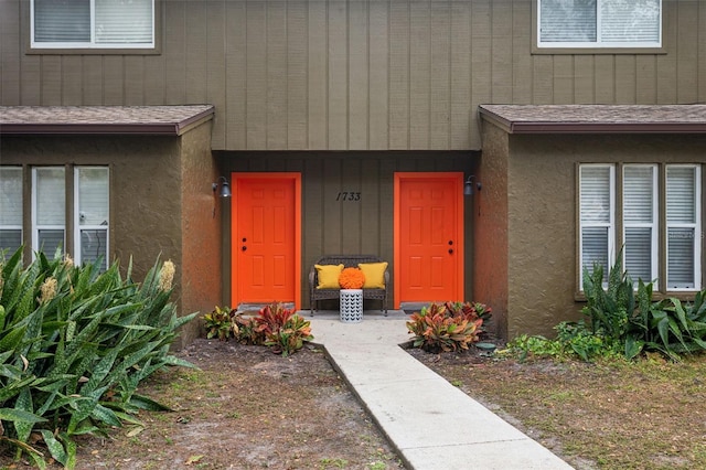 property entrance with stucco siding and a shingled roof